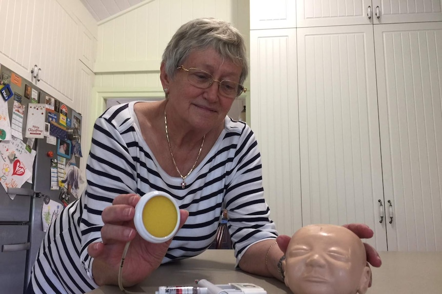 Janet Vacca holds a vacuum cup and demonstrates how it is used with a model of a child's head