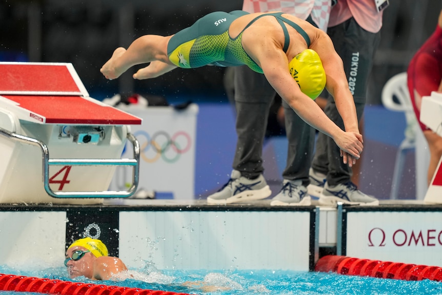 An Australian female swimmer dives into the pool during a relay.