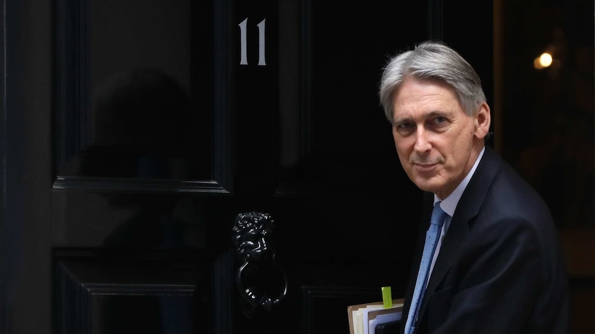 Chancellor Philip Hammond wearing a suit leaving 11 Downing Street