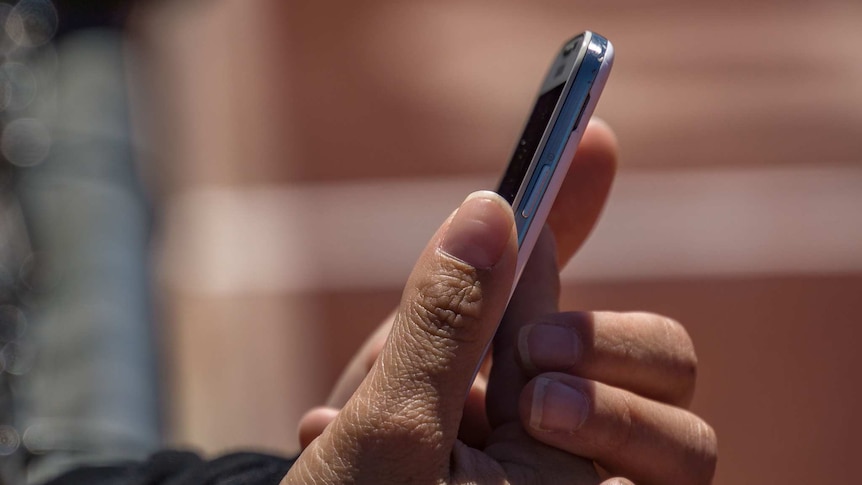 A person's hands holding a silver and white mobile phone.