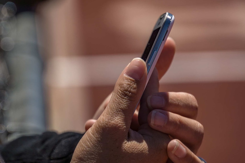 A person's hands holding a silver and white mobile phone.
