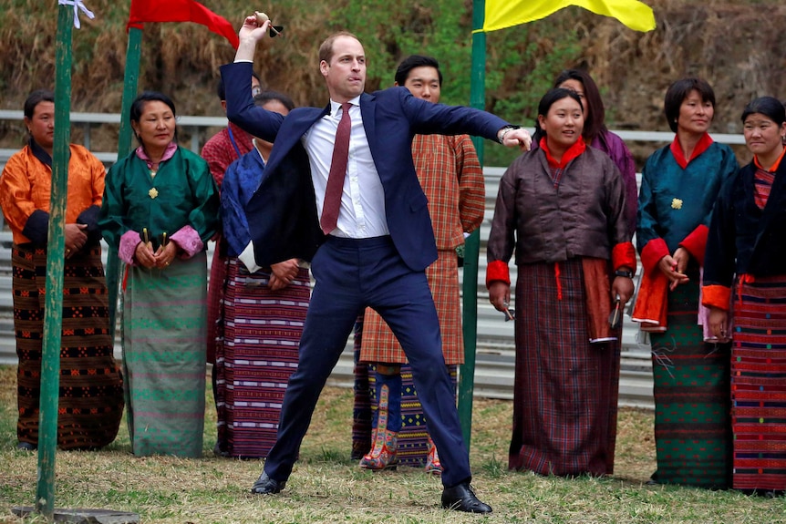 Prince William throws a dart.