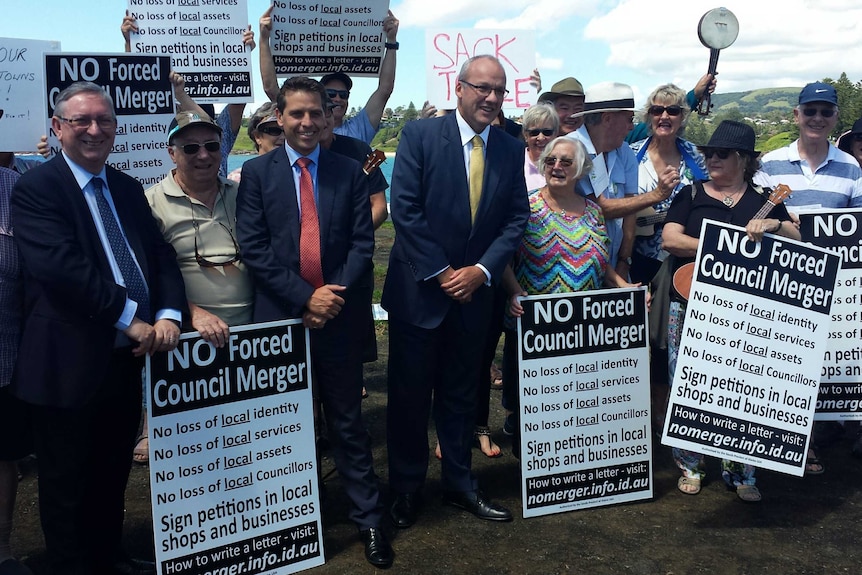 New South Wales Labor leader Luke Foley with protesters holding placards against forced council amalgamations.