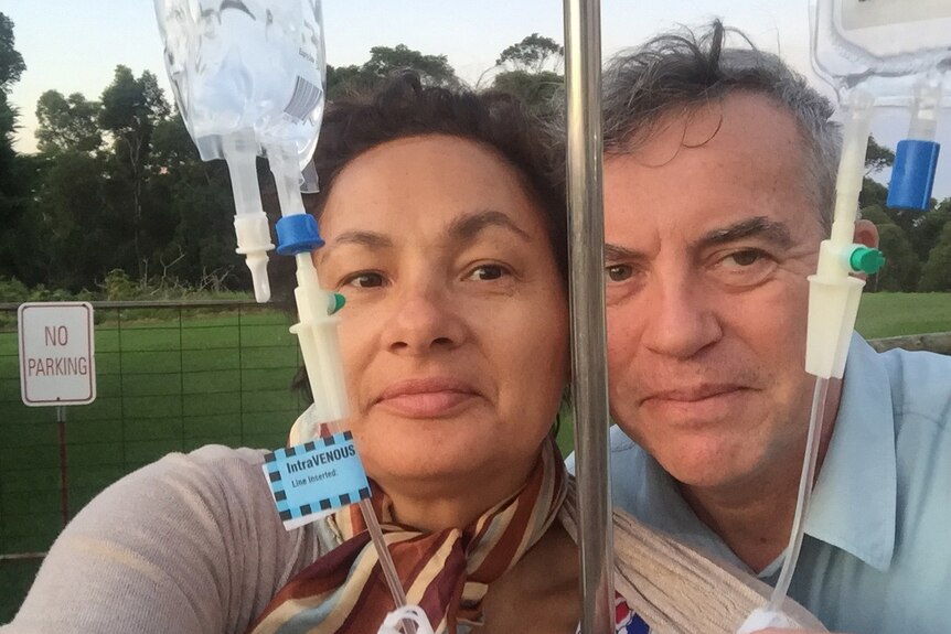 Jill Emberson and her husband Ken with an IV bag and pole.
