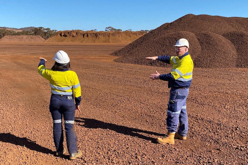 Two mine workers, one man one woman, gesticulate on a mine site 400km east of Perth.