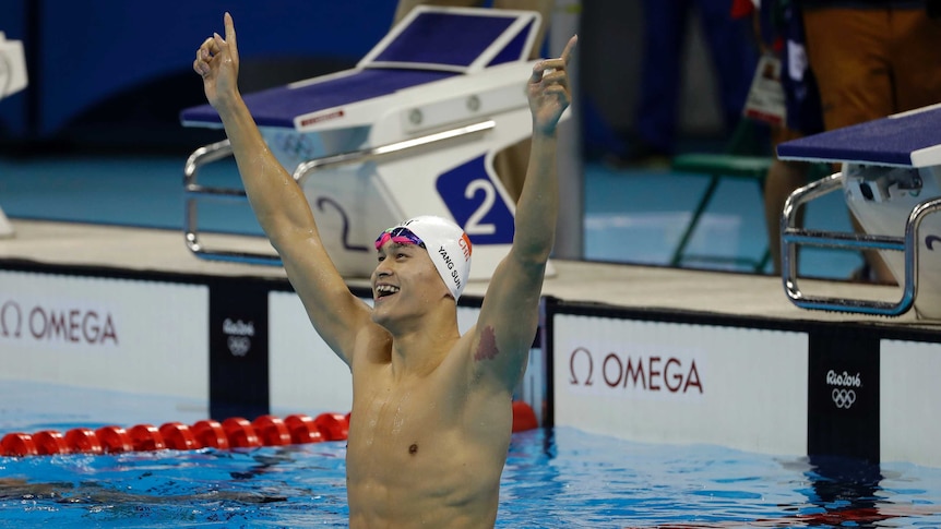 Sun Yang celebrates with his arms in the arm while standing in a swimming pool