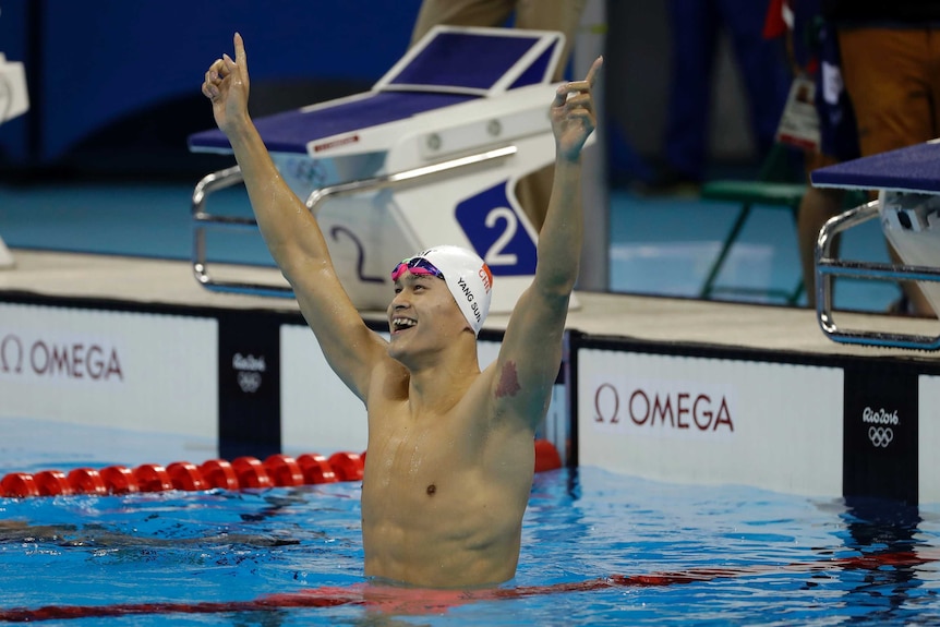 Sun Yang celebrates with his arms in the arm while standing in a swimming pool