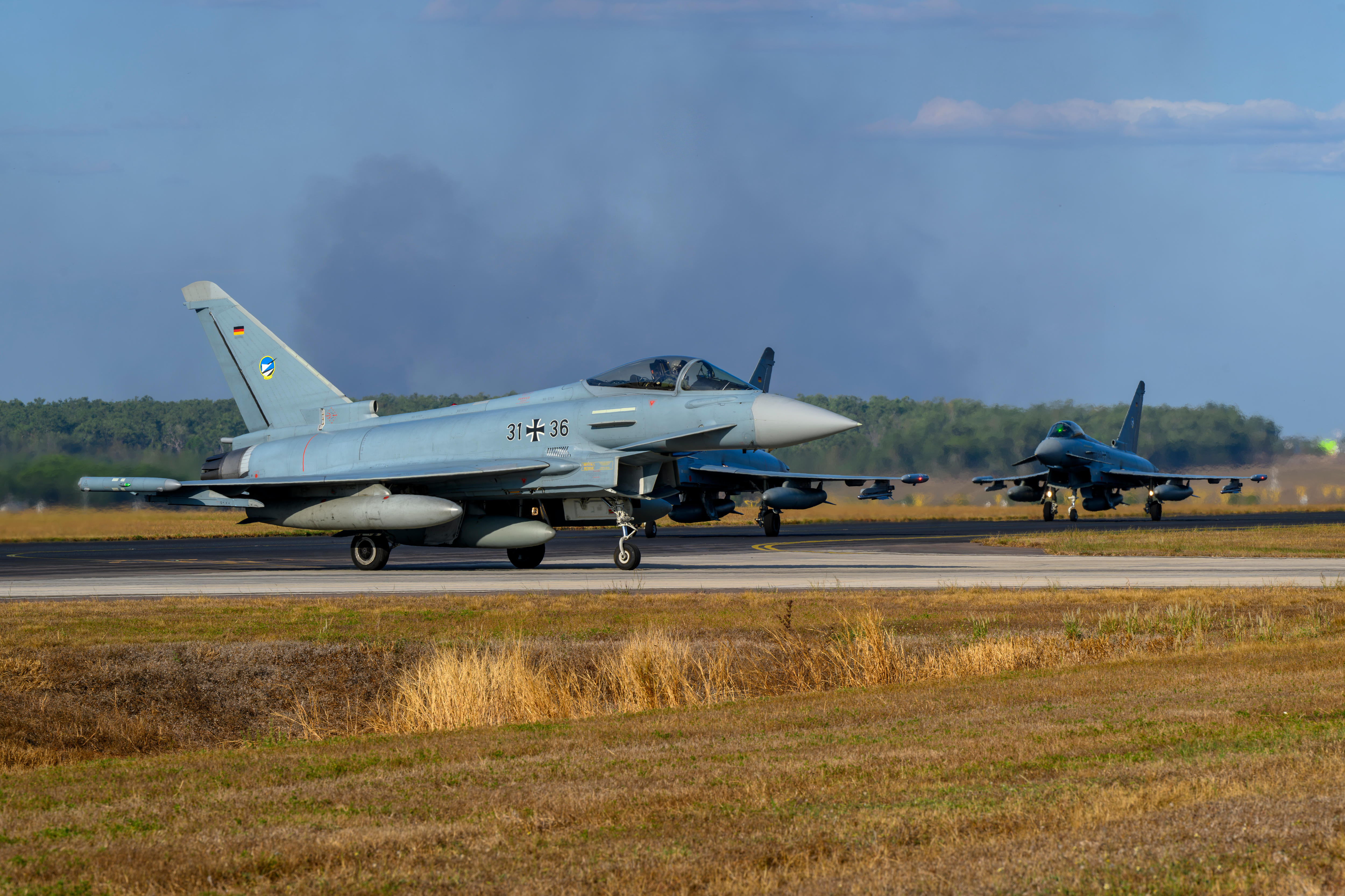 Three fighter jets on a runway.