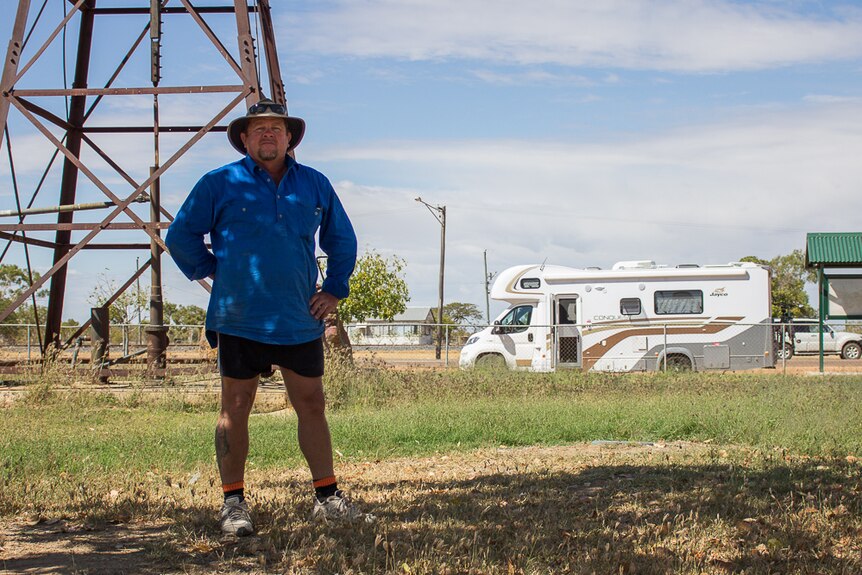A man stands in front of a windmill in Hughenden.