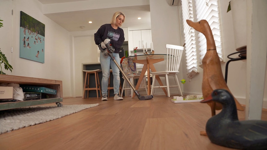A woman vacuums the floor of a home.