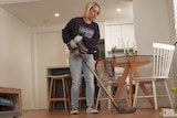 A woman vacuums the floor of a home.