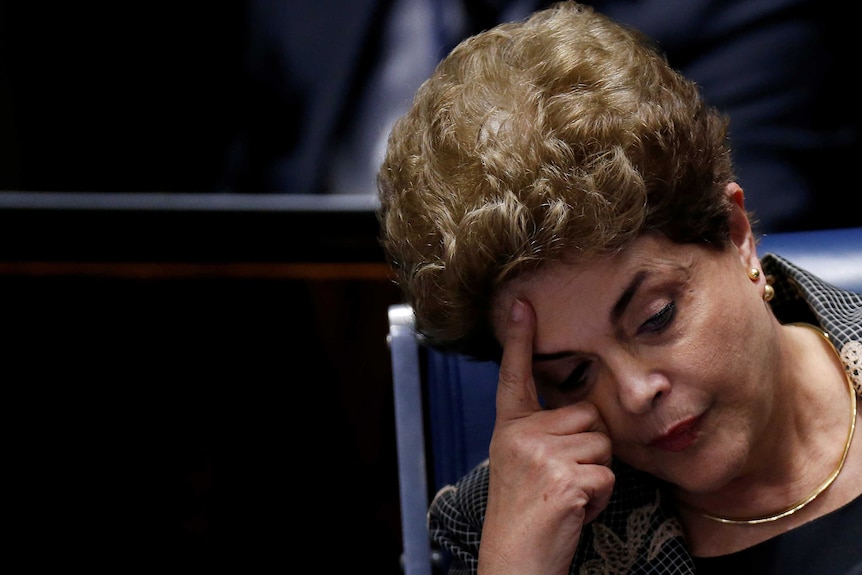Dilma Rousseff rests her head against her hand.
