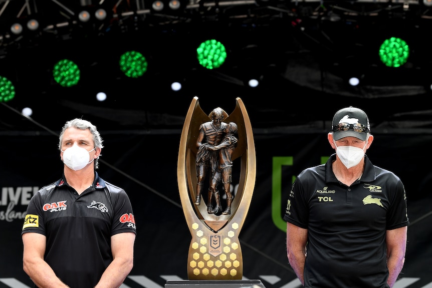 Penrith Panthers coach Ivan Cleary and South Sydney Rabbitohs coach Wayne Bennett stand beside the NRL premiership trophy.