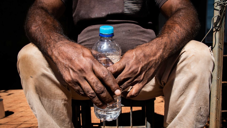 Water bottle being held by an man in a remote Indigenous community.