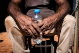 Water bottle being held by an man in a remote Indigenous community.
