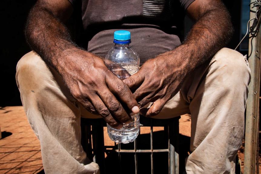 Water bottle being held by an man in a remote Indigenous community.