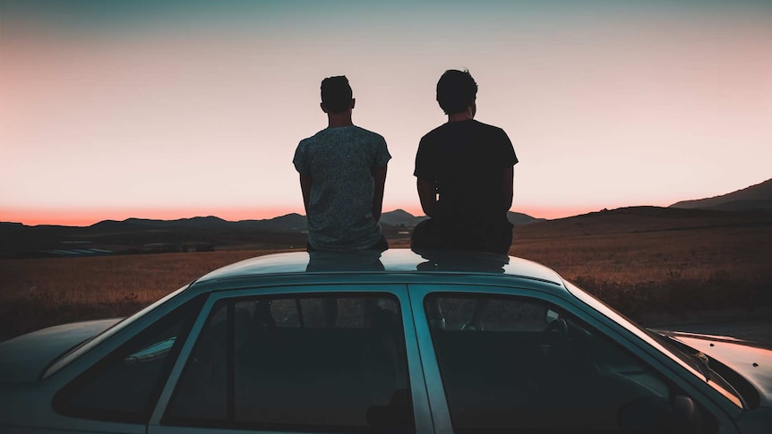 Two men sitting on top of a car to depict social connection