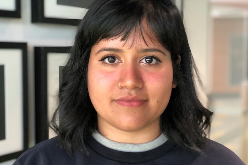 Student Tayeba Quddus looking at the camera standing in a hallway.