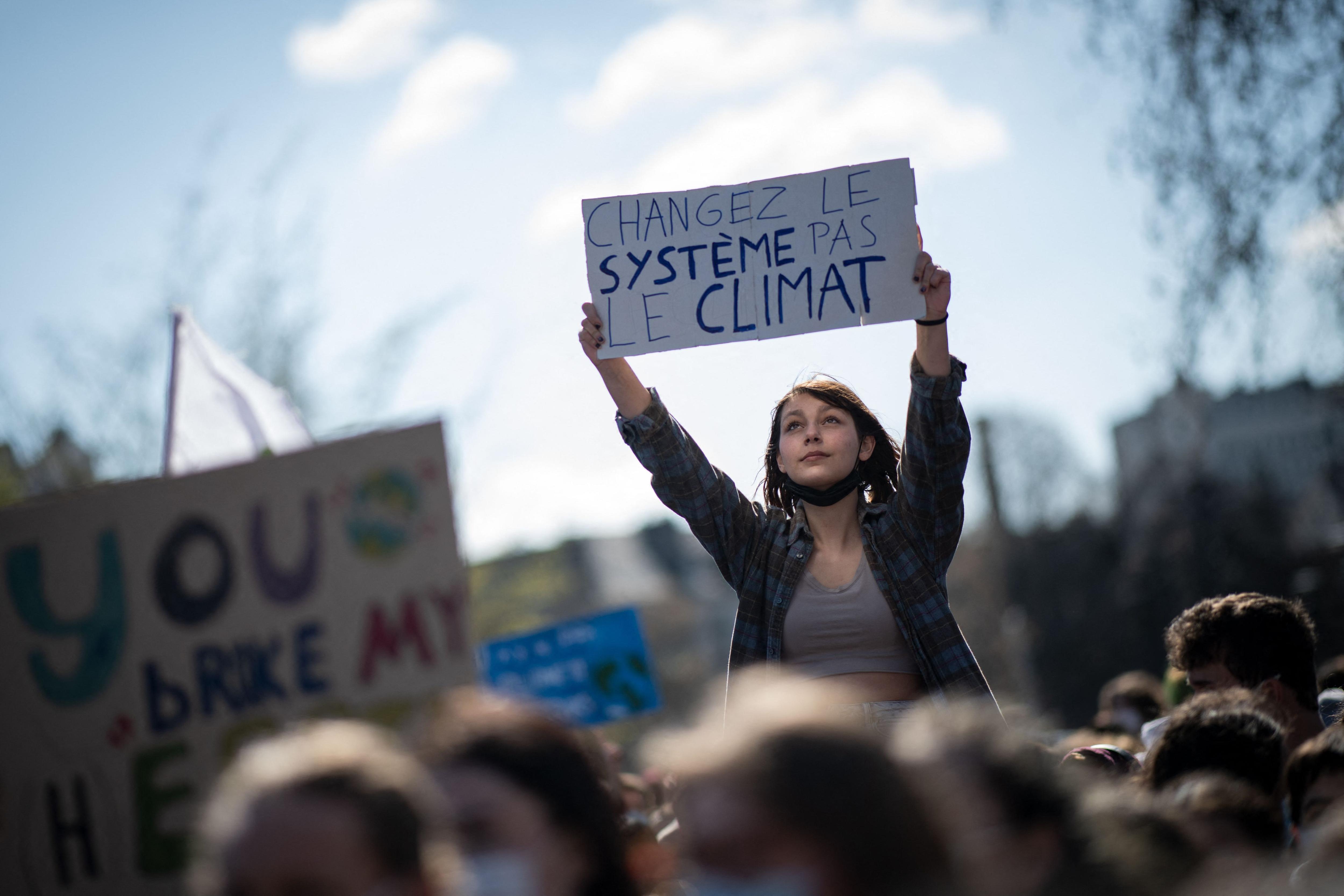A woman in Nantes holds a placard reading "Change the system, not the climate"