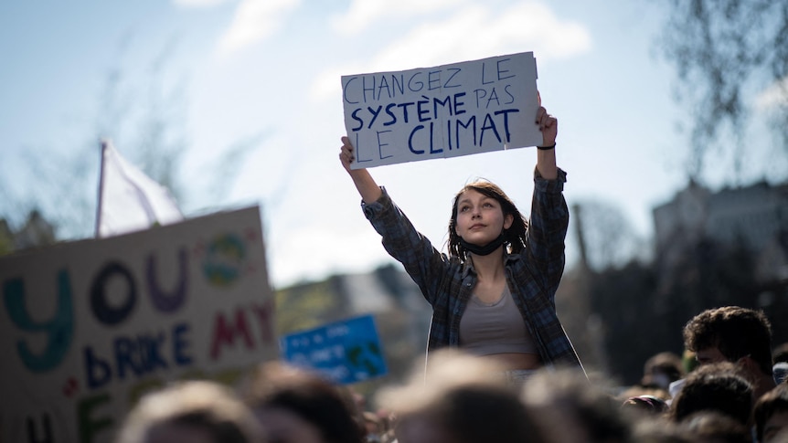 A woman in Nantes holds a placard reading "Change the system, not the climate"