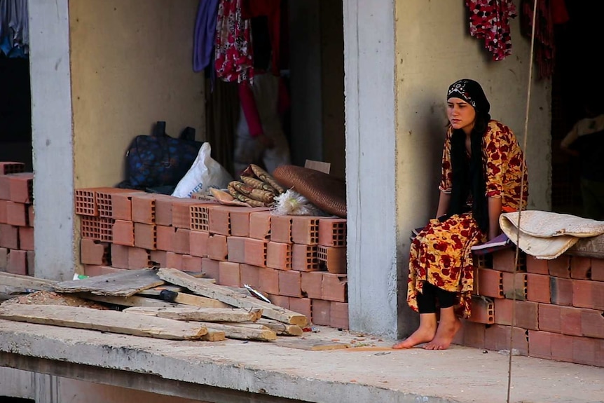 A Yazidi women sits in a high-rise construction sight converted into a makeshift refugee camp in Zakho