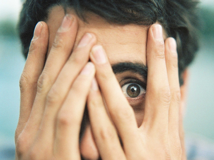 man looking through fingers