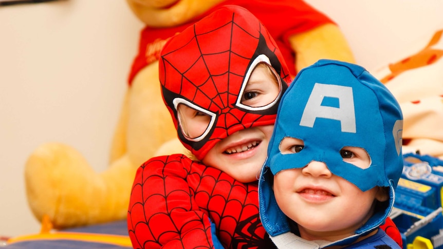 A boy in a Spiderman costume hugs a boy in a Captain America outfit
