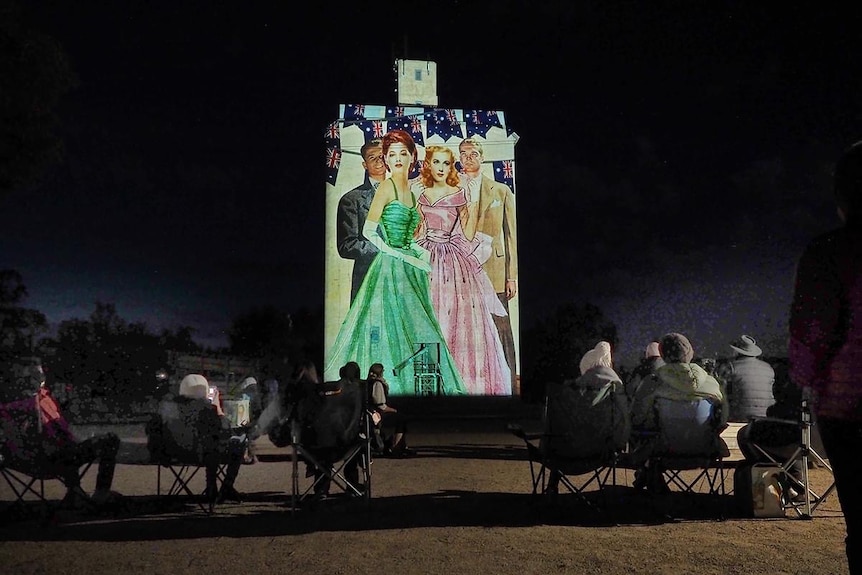 A silo with an art image of women projected on it