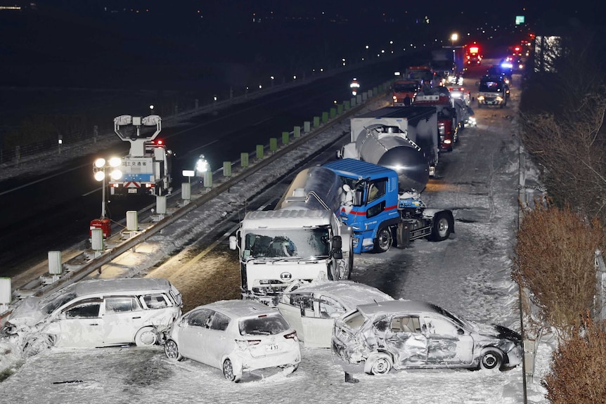 Crashed cars and trucks on an icy road at night time.