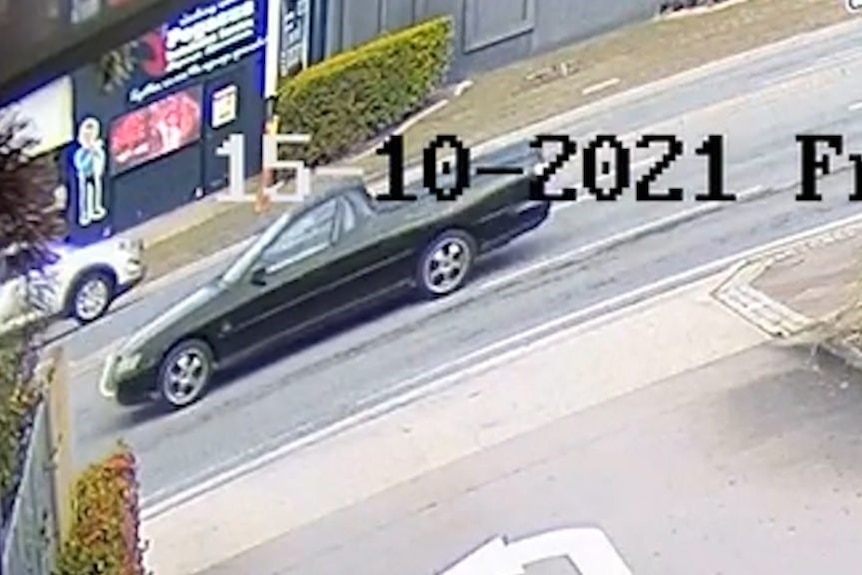 A still from CCTV showing a dark coloured ute driving along a street