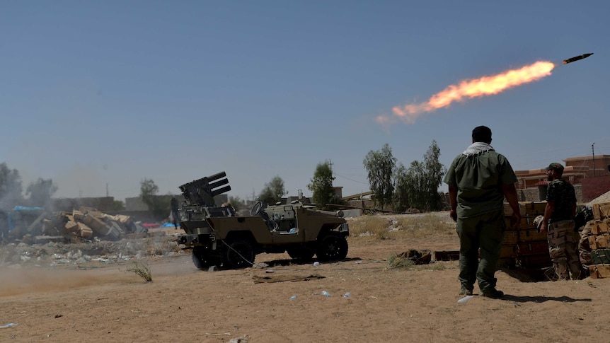 Shiite fighters launch a rocket towards Islamic State militants on the outskirt of Baiji
