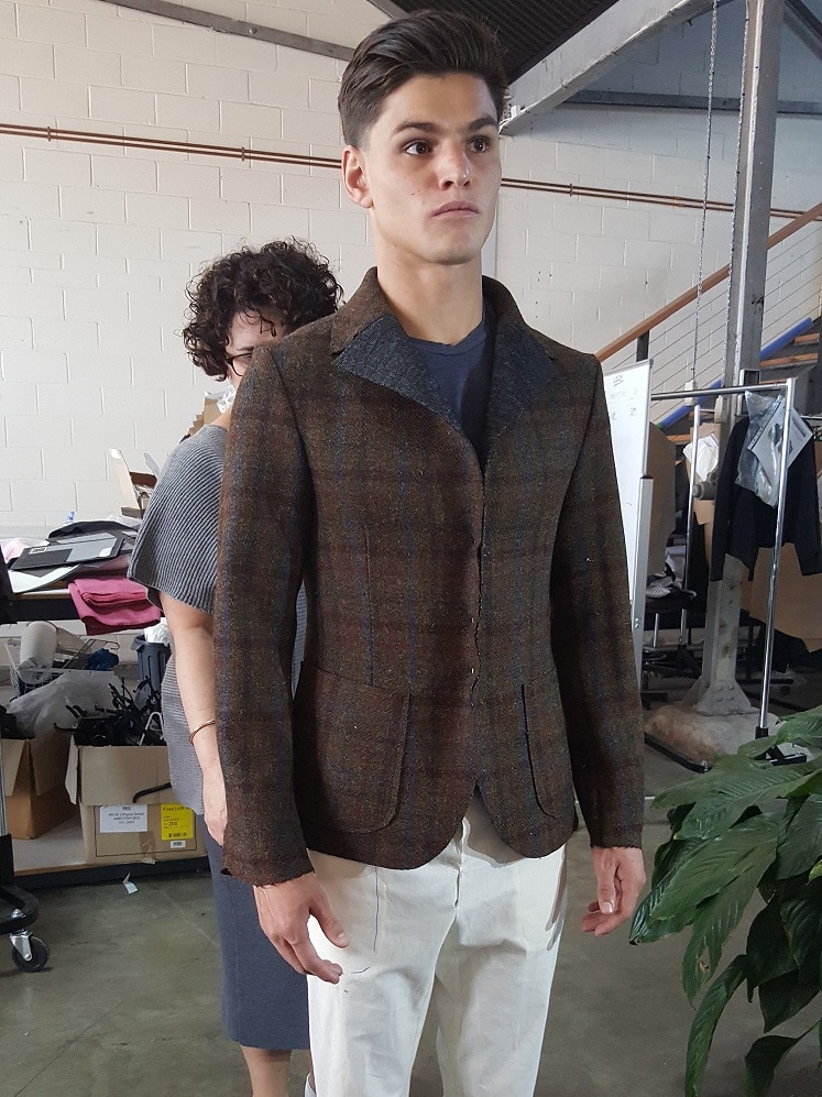 A male model stands while a tailor adjusts a suit