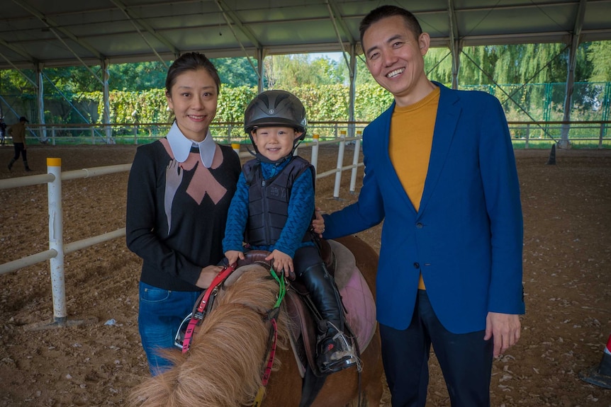 A Chinese boy on a pony with his mother and father along side him.