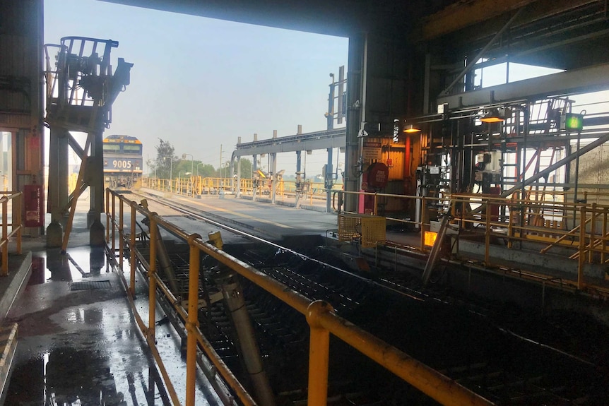 A train stopped on the tracks just outside a coal unloading station.