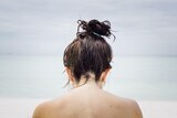 Back of woman's head with wet hair in a bun in a story about tips for managing oily hair.
