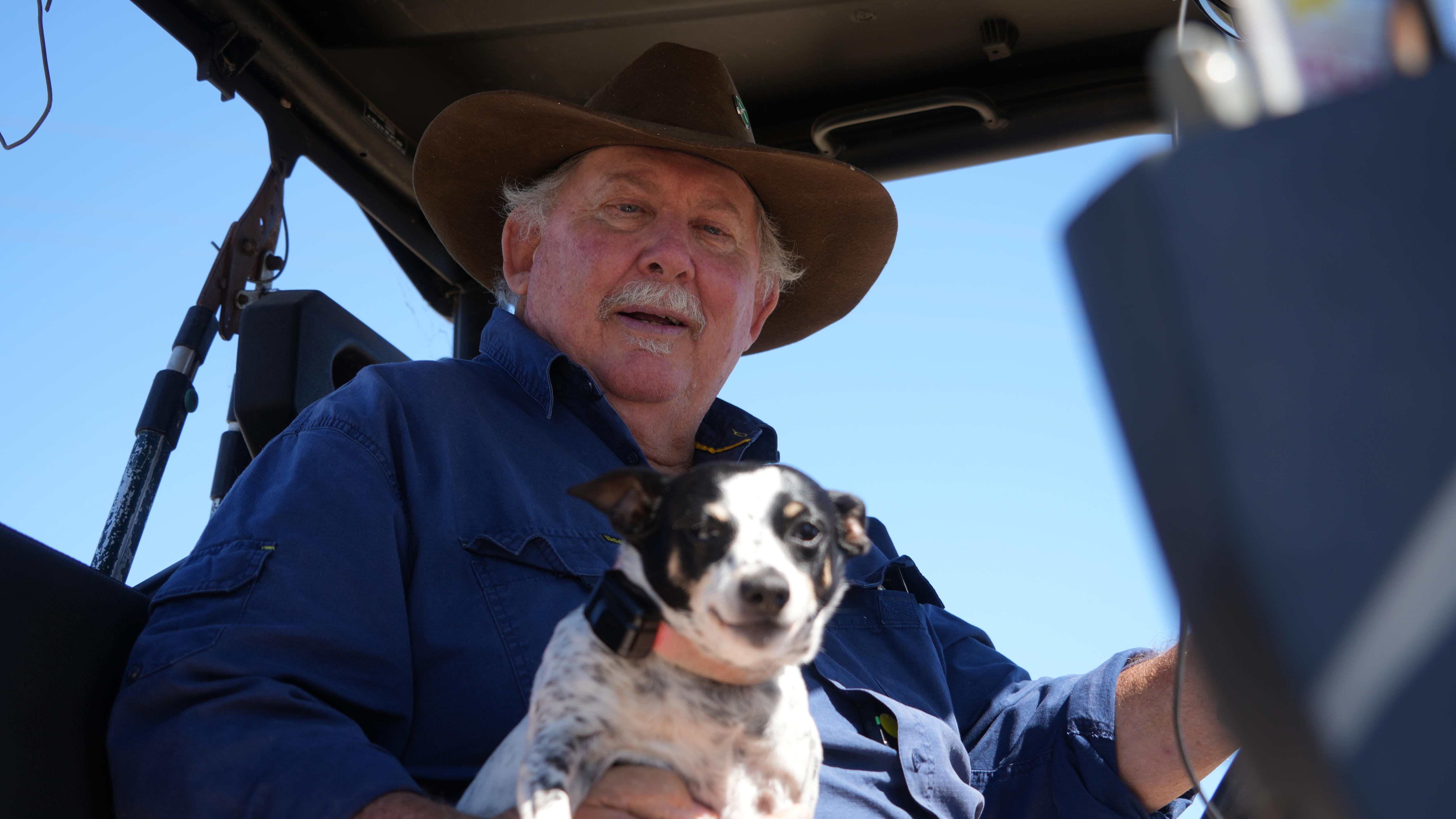 Man with mustache and button-down shirt with puppy on ATV