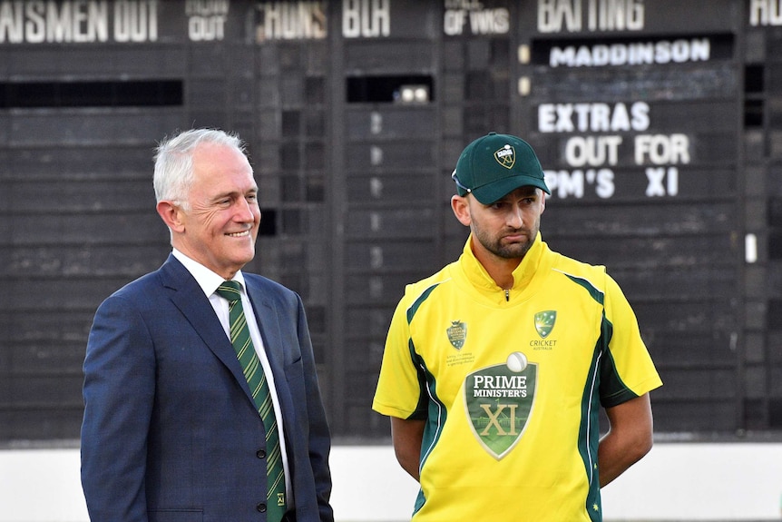 Prime Minister Malcolm Turnbull and Australia's Nathan Lyon pose in front of the scoreboard.