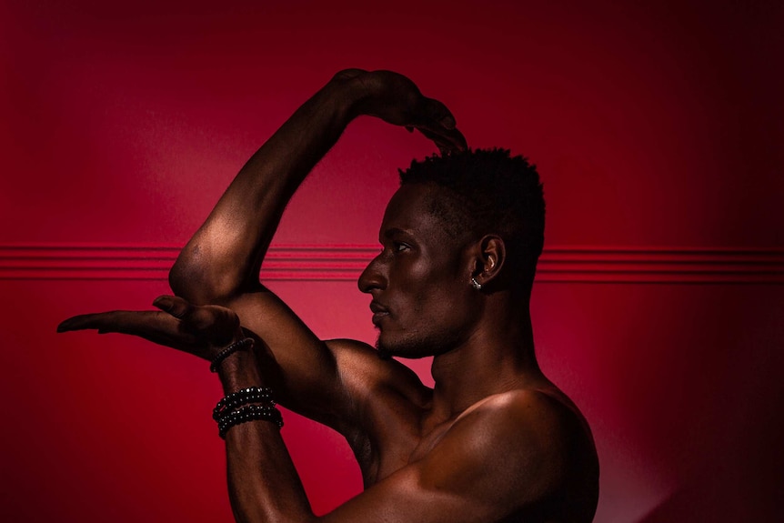 Profile silhouette portrait of performer Dashaun Wesley, against a pink-red background.