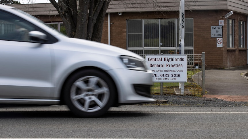 A silver car drives past the Central Highlands General Practice in Ouse, a brown brick building. 