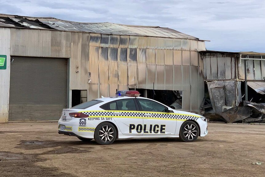 A police car outside a damaged shed
