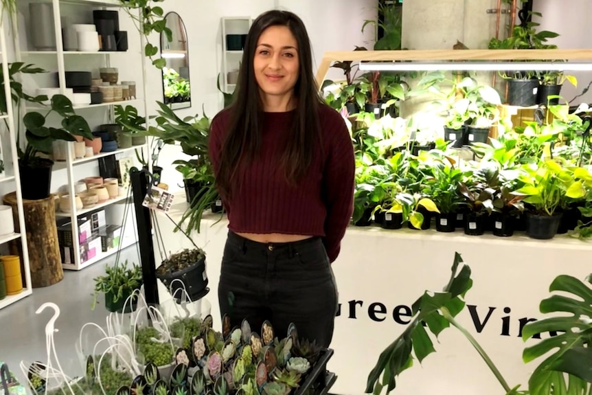 A lady stands in a plant shop smiling