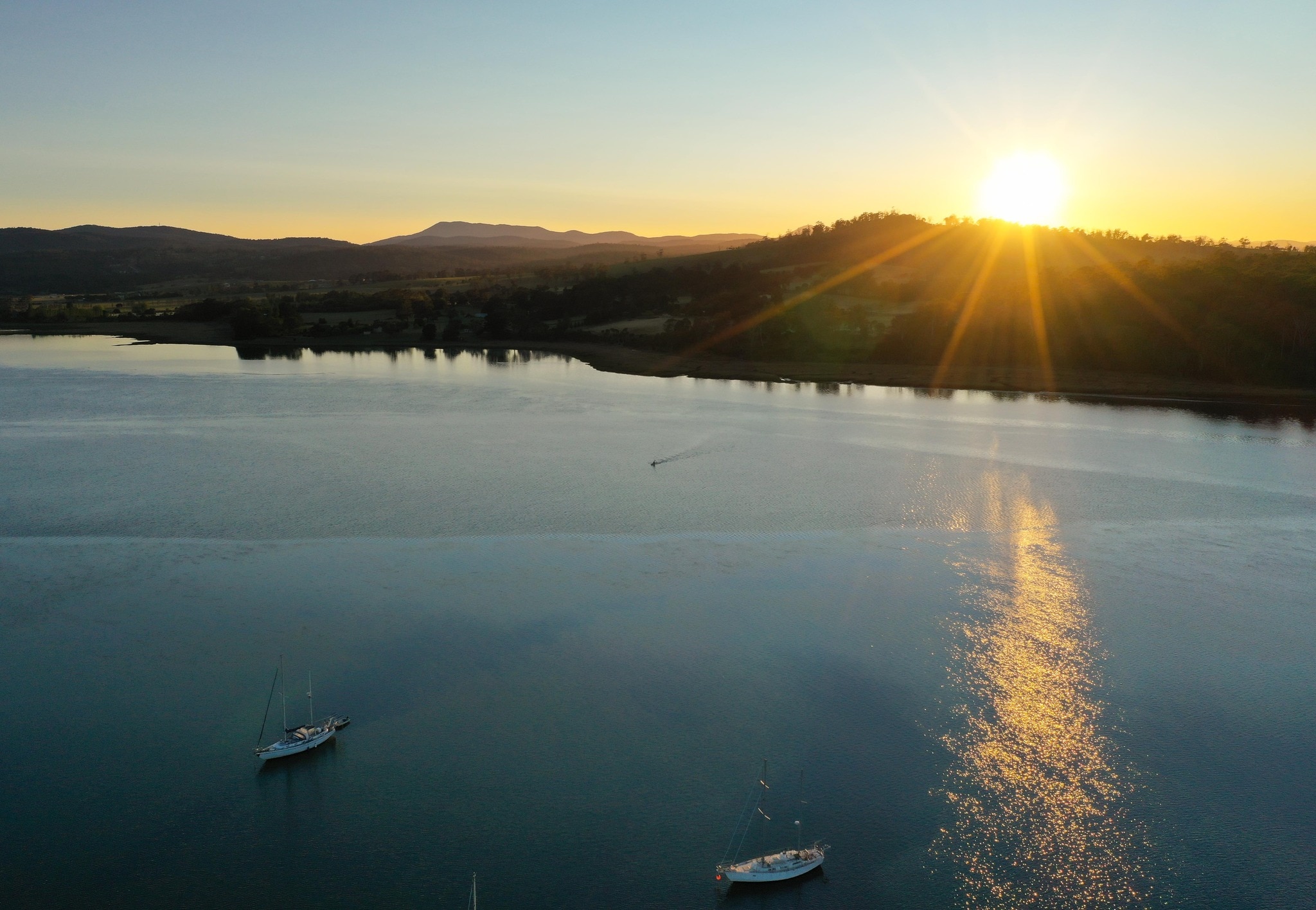 An aerial picture of a river with the sun low in the sky above.