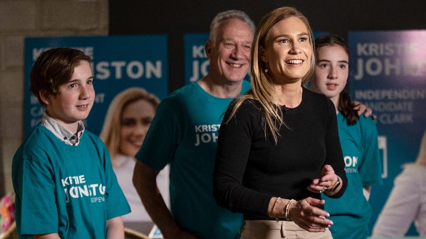 A woman smiles as her children and partner stand behind her