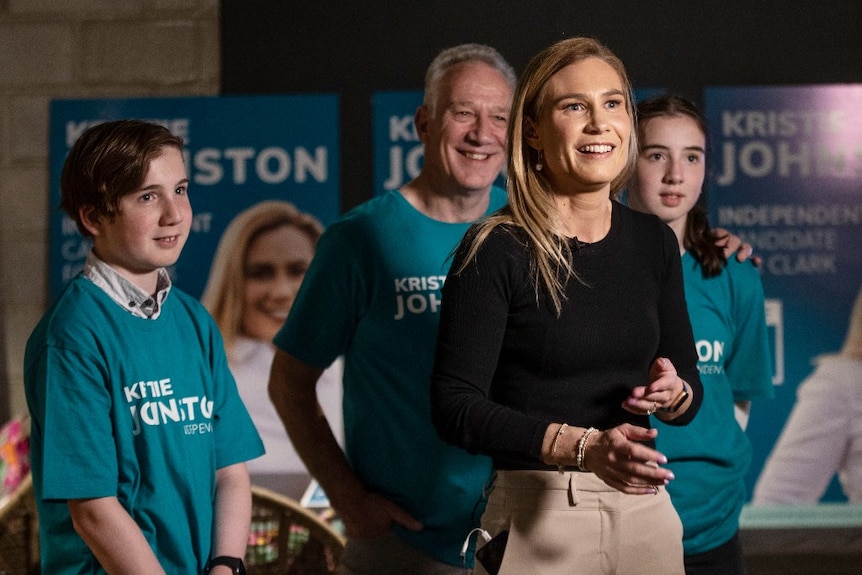 A woman smiles as her children and partner stand behind her