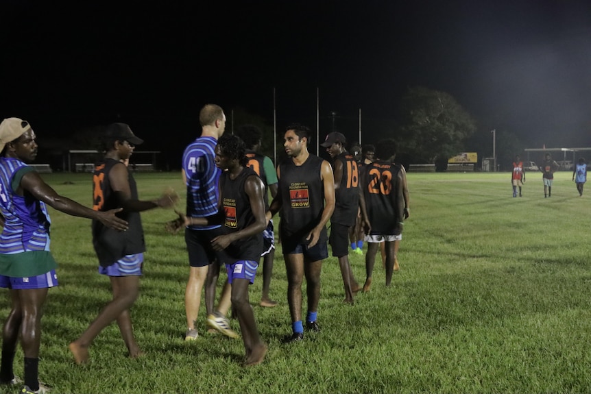 Football players shake hands on oval