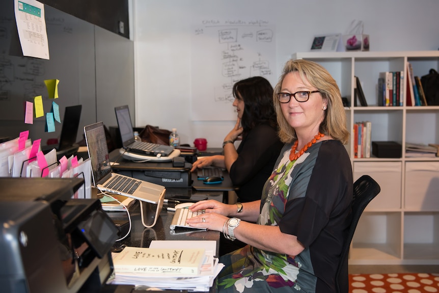 Michelle Gallaher sits at a desk in an office