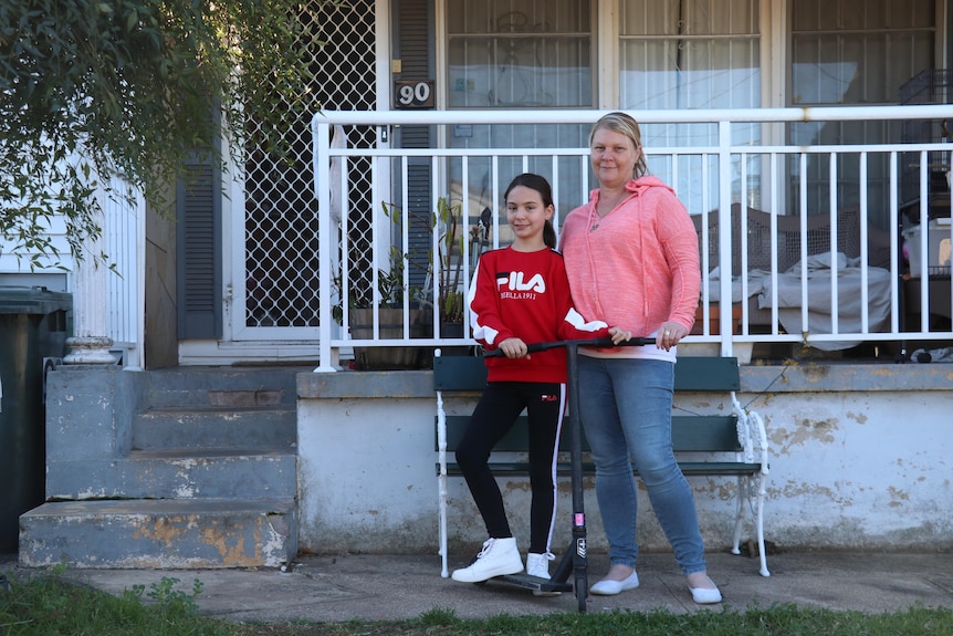 A mum and her daughter out the front of a house