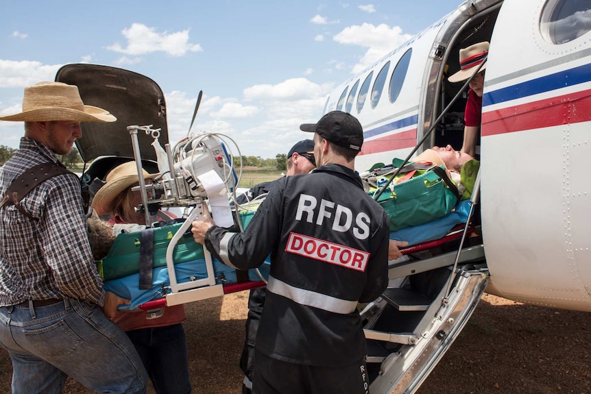 Medical staff loading a patient into a small plane.