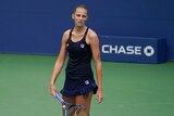 A tennis player frowns as she looks up the court after losing her singles match at the US Open.
