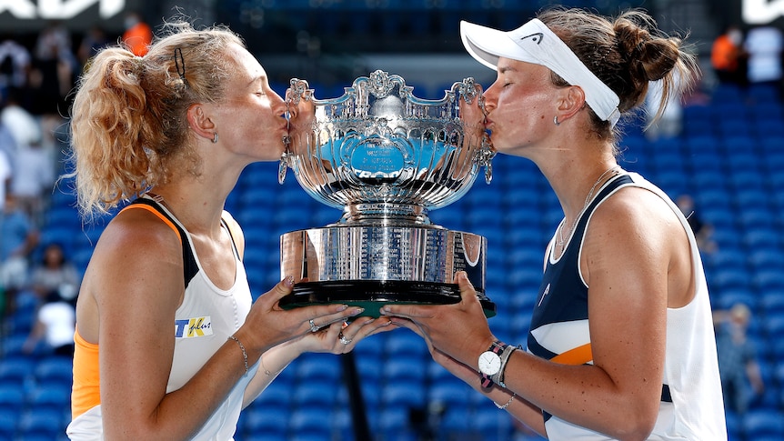 Two Czech female tennis players hold the Australian Open women's doubles trophy.